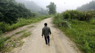 Sixty-one-year-old villager Xiong Dejun walks towards a bus station, on his way to get an X-ray examination for his lungs at a hospital in Heshan village. Jason Lee / Reuters