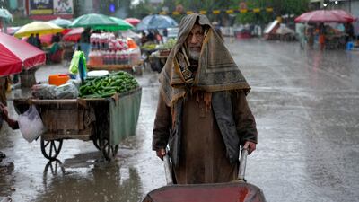 An Afghan laborer pushes a wheelbarrow during a rainy day at the old market in Kabul, Afghanistan, Tuesday, May 3, 2022. (AP Photo / Ebrahim Noroozi)