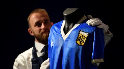 A Sotheby's art handler poses with the shirt worn by the late Argentinian great Diego Maradona during the 1986 World Cup, ahead of it being auctioned by Sotheby's in London on Wednesday, April 20, 2022. Reuters