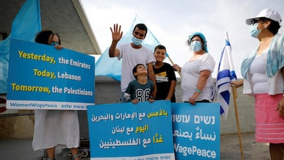 A man and his sons pose for a photograph as they stand behind a placard belonging activists from "Women Wage Peace", close to a military base leading to the border crossing with Lebanon at Rosh Hanikra, northern Israel. Reuters