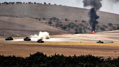 Turkish army tanks and alleged Syrian opposition fighter trucks positioned 2km west of Jarabulus on the Syria-Turkey border on August 24,2016. Picture taken from the border city of Karkamis. Bulent Kilic / AFP