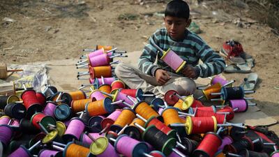 A young Indian boy rolls kite twine on a roadside in Amritsar, India. Raminder Pal Singh / EPA