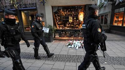 French gendarmes walk past flowers and candles laid in the street in tribute to the victims of a deadly shooting in Strasbourg, France. AFP