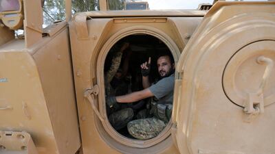 A Turkey-backed Syrian rebel gestures as they drive their military tank near the border town of Tal Abyad. Reuters