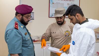 Mohammed Waheedi and Ali Al Shamsi of the Ajman Police Crime Scenes Investigative Unit discuss new evidence with director of Ajman CSI Abdullah Yousuf Al Awadi. Navin Khianey for The National
