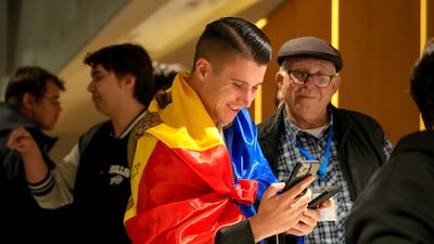 A supporter of the pro-EU Party of Action and Solidarity (PAS) draped in the Moldovan flag checks results on a phone after the polls closed. AP