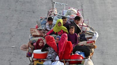Syrian families from the southeastern Idlib province and the northern countryside of Hama fleeing battles with trucks loaded with their belongings, drive past a flock of sheep on the highway, as they drive near Maaret al-Numan in the southern Idlib province. AFP / Omar HAJ KADOUR