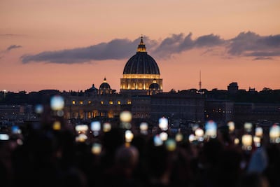 People use smartphones to capture the sunset around St Peter's Basilica on April 24. AFP