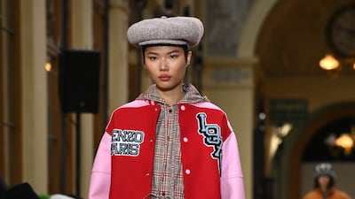 A dress in clashing checked fabrics is worn with a varsity jacket decorated with the date Kenzo first opened its doors in 1970.