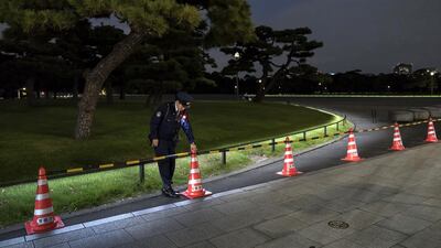 A police officer places a traffic cone outside the Imperial Palace at night as Japan prepares for the enthronement of Emperor Naruhito. Getty