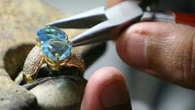Worker fitting stones on different jewelry item in the mass production area of Damas factory in Dubai Multi Commodities Center.