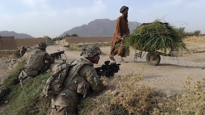 An Afghan farmer walks past as US soldiers keep guard while troops seal a canal running through Highway 1 on the outskirts of Kandala village in Kandahar on August 6, 2011, as part of a mission to secure strategic roads against the placement of improvised explosive devices by Taliban insurgents. AFP