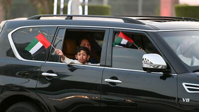 A child waves the UAE flag during the long weekend at Abu Dhabi Corniche. Khushnum Bhandari / The National