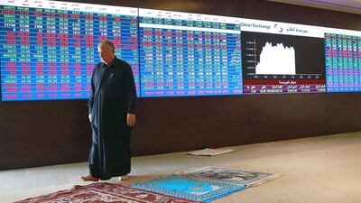 A man walks past the Qatar stock exchange board in Doha. Mohammed Dabbous / Reuters