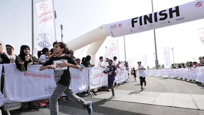 A young competitor is elated to cross the finish line at the Abu Dhabi Zayed Marathon in March 2016. Adel Al Nuaimi / Al Ittihad
