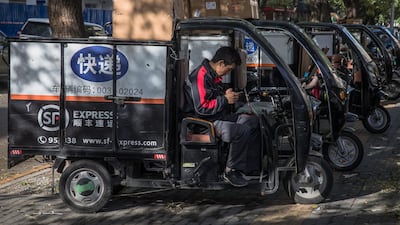 An employee sits in a a three-wheeled vehicle with packages loaded on top for delivery before Singles Day in Beijing, China. EPA