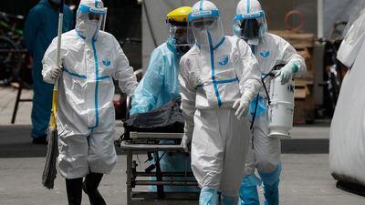 Health workers in protective suits transport a corpse at a hospital in Manila, Philippines. AP Photo