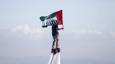 A man on a flyboard carries the flag at Ras Al Khaimah's Corniche. Reem Mohammed / The National