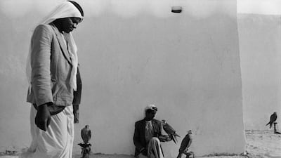A falconer sits with his birds outside what is probably the walls of Qasr Al Hosn in Abu Dhabi, 1964.