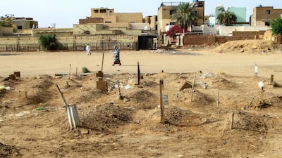 A Sudanese woman walks past graves of people killed during clashes in Omdurman. AFP