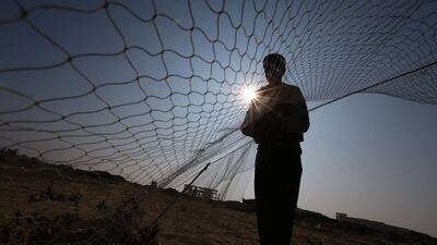 A Palestinian sets up a net to catch songbirds at the site of Gaza destroyed airport, in Rafah. Rueters
