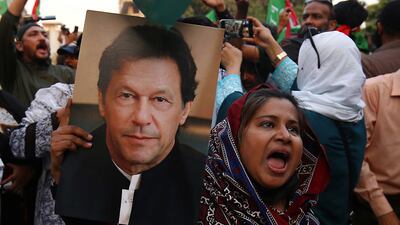 A supporters holds a portrait of Mr Khan. EPA