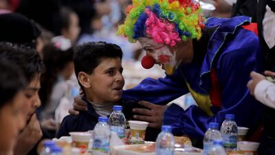 A clown entertains a boy as orphaned Syrian children and widows share an iftar, during Ramadan, on April 12, in the city of Al Bab in the north of Syria's Aleppo province. AFP