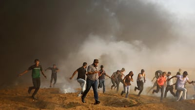 Protesters run to cover from tear gas fired by Israeli troops, while others burn tires near fence of the Gaza Strip border with Israel, during a protest east of Gaza City. AP Photo
