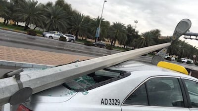 A lappost falls onto a taxi at the junction of Hazza bin Zayed Street and Mubarak bin Mohammed Street near the Shaheen Supermarket and Khalidiya Police Station. Ramona Ruiz / The National