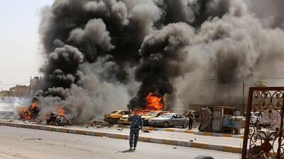 Policemen stand near burning vehicles moments after one in a series of bombs hit the Shiite stronghold of Sadr City in Baghdadon on May 13, 2014. Karim Kadim / AP Photo
