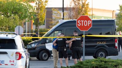 Police officers embrace at the scene of the shooting in Mississauga.