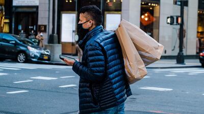 A pedestrian wearing a protective mask carries shopping bags across Fifth Avenue in New York. Bloomberg