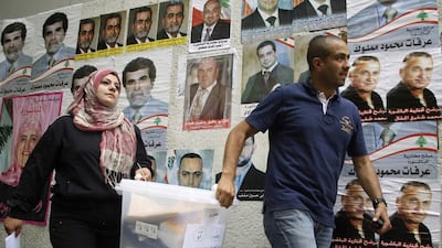 Lebanese government election officials walk past a wall on which posters of Lebanese candidates running in the country's municipal election are pasted. Mohamed Azakir / Reuters