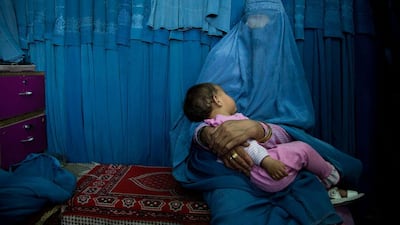 A woman waits with her child in front a changing room to try on a new burqa.