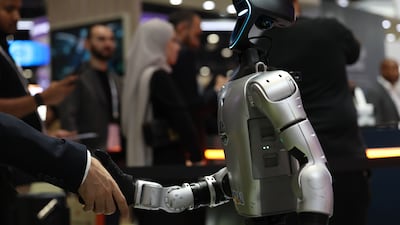 A visitor shakes hands with a robot at the AI Everything Abu Dhabi conference on October 6. Trust is central to the debate about the technology’s future. EPA