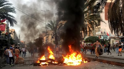 Demonstrators walk near burning tires in Tripoli, Lebanon. REUTERS
