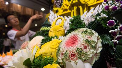 A Thai man helps put together an elaborate decoration display with carved fruits and vegetables during a fruit and vegetable carving competition in Bangkok. Robert Schmidt / AFP
