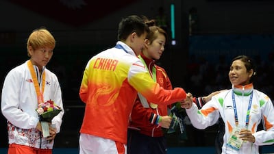 South Korea’s silver medallist Park Ji-na, left, looks on as China’s gold medallist Yin Junhua and Vietnam’s bronze medallist Luu Thi Duyen, centre, shake hands with India’s Sarita Devi after she refused to accept the bronze during the women’s boxing medal ceremony on Wednesday. Indranil Mukherjee / AFP