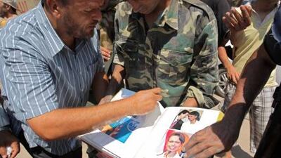Rebel fighters look through an album they found inside Muammar Qaddafi's compound in Bab Al-Aziziya in Tripoli on Wednesday.