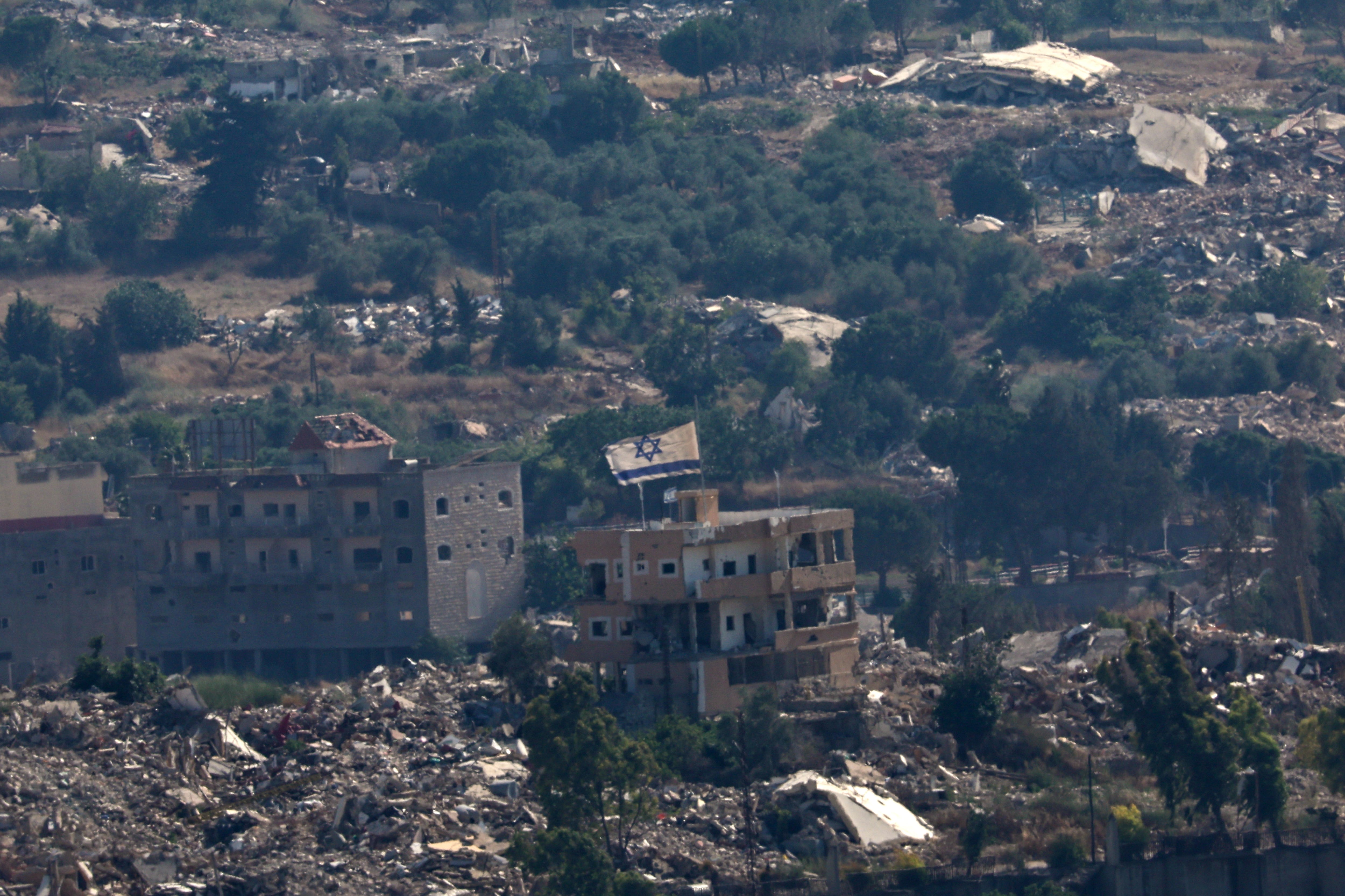 An Israeli flag flutters from the roof of a severely damaged house in south Lebanon. EPA