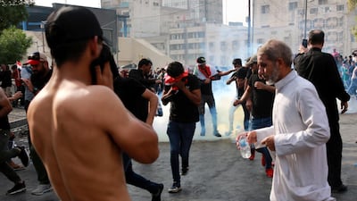 Iraqi protesters run for cover amid tear gas fired by policemen during a demonstration at Tahrir Square, central Baghdad. EPA