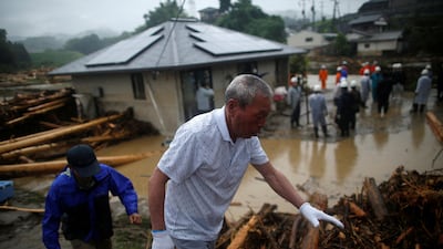 Residents walk on debris washed up by heavy rain as rescue workers search for missing people near a damaged house at Yamada district in Asakura, Fukuoka prefecture, Japan, on July 7, 2017. Issei Kato / Reuters
