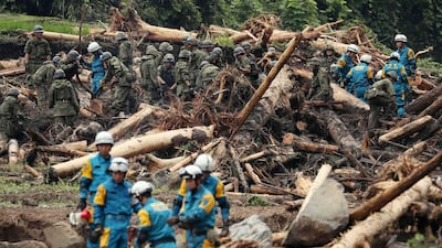 Policemen and members of Japan's Ground Self-Defense Force take part in seach operations for missing people in a flooded area in Toho, Fukuoka prefecture, on July 8, 2017. The death toll from heavy rains and flooding in southern Japan has risen to 15, a government official said, as rescuers continued work to evacuate isolated survivors. / AFP PHOTO / JIJI PRESS / STR / Japan OUT