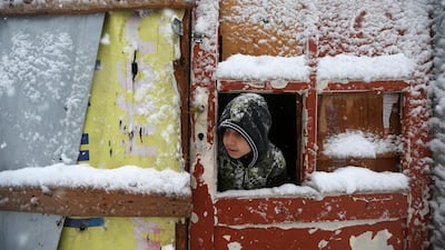 A boy looks out of his tent in winter at a refugee camp in Deir Zannoun village, Lebanon. AP