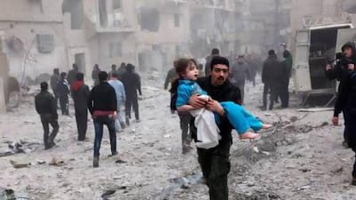 A man holds a child in his arms in Aleppo after an airstrike destroyed a house and killed and injured several people.