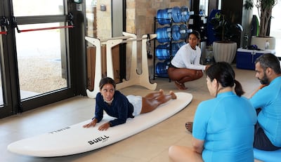 Surf guide Mouna Boumar demonstrates how to safely attempt to stand up while surfing. Pawan Singh / The National