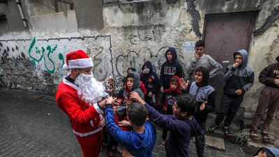 A Palestinian man dressed in a Santa Claus costume spreads happiness among the camp children amid the ongoing coronavirus COVID-19 pandemic, in Al Shatea refugee camp in Gaza City. EPA