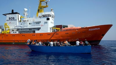 In this Aug. 29, 2017 file photo, African migrants float on a wooden boat next to a rescue ship during a search and rescue operation conducted by SOS Mediterranee's Acquarius ship and MSF (Doctors Without Borders) NGOs, in the Mediterranean Sea, north of Libyan coast. Darko Bandic / AP