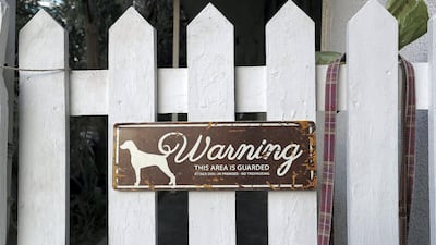 A sign on a white picket fence of a villa warns passers-by of a dog. Pawan Singh / The National