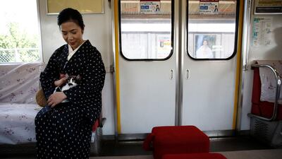 A woman wearing a Kimono holds a cat, in a train cat cafe. Kim Kyung-Hoon / Reuters